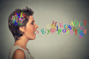 woman talking with alphabet letters in her head coming out of open mouth
